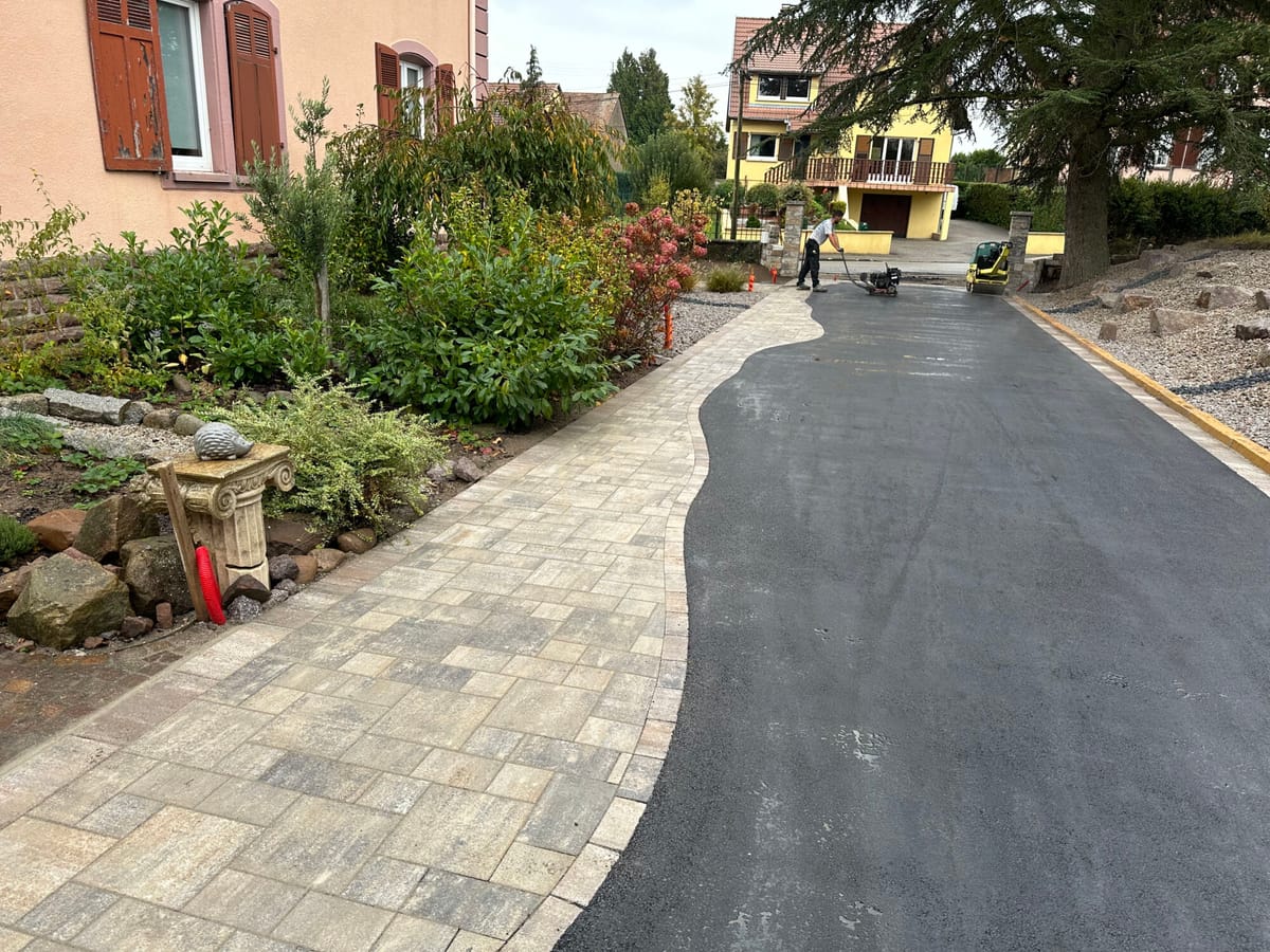 Allée en enrobé au tracé courbe traversant un jardin paysager