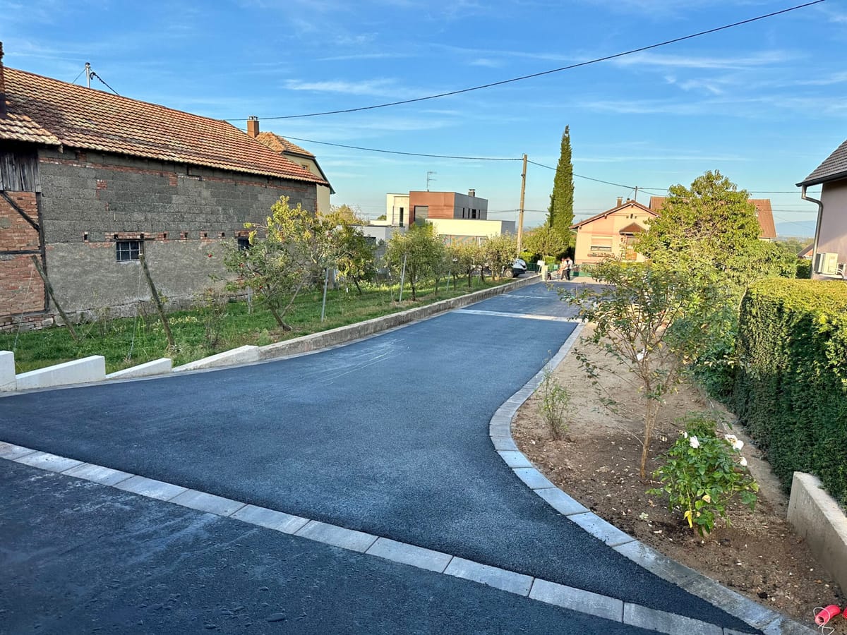 Allée en enrobé noir avec bordures et plantations en périphérie
