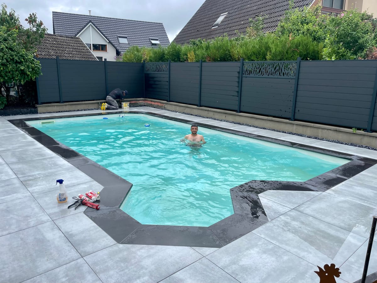 Clôture occultante sombre entourant une piscine et sa plage