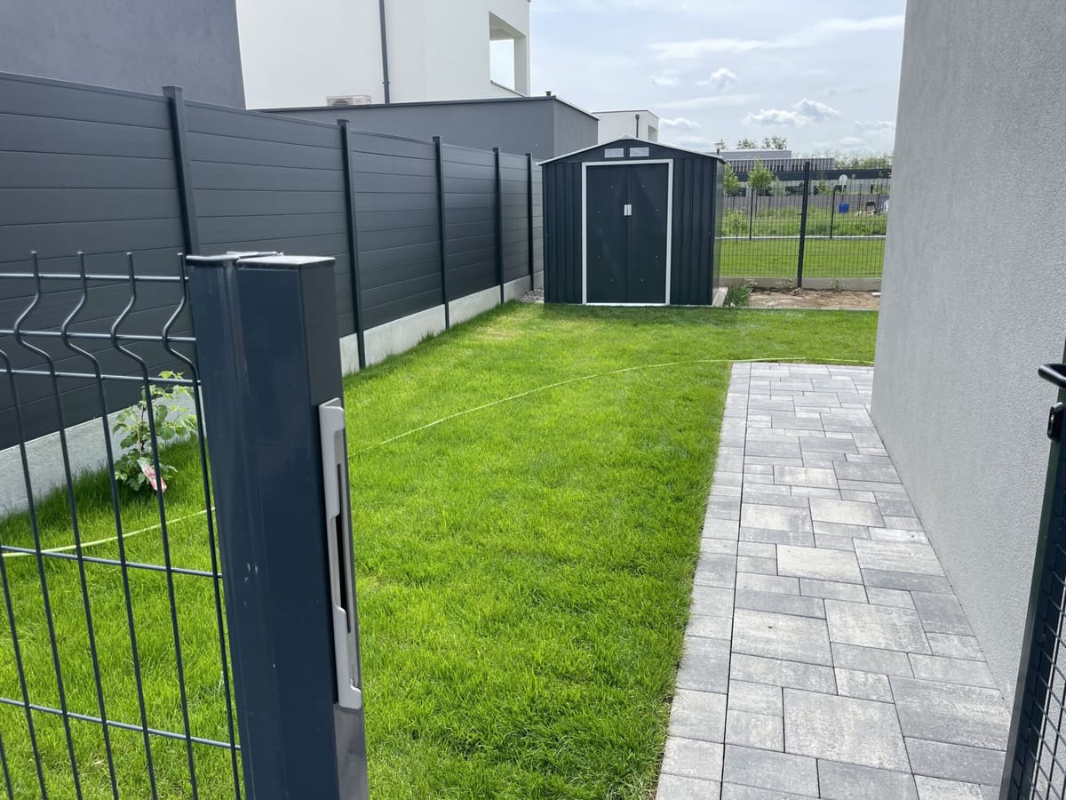 Clôture rigide avec portail et pelouse engazonnée en fond de jardin