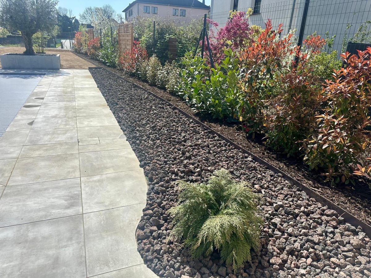 Cour pavée avec banc et massifs plantés à Village-Neuf