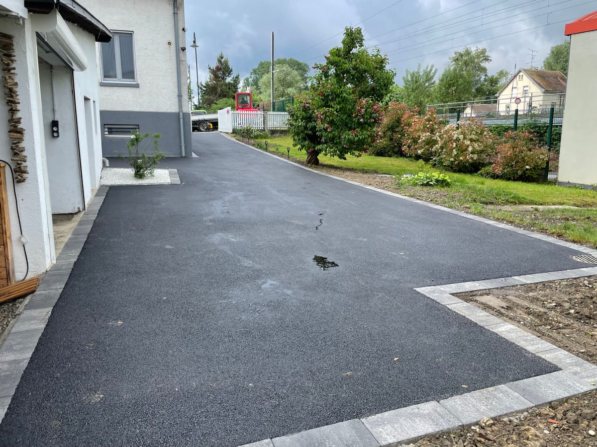 Accès véhicule en enrobé délimité par une bordure et une bande pavée