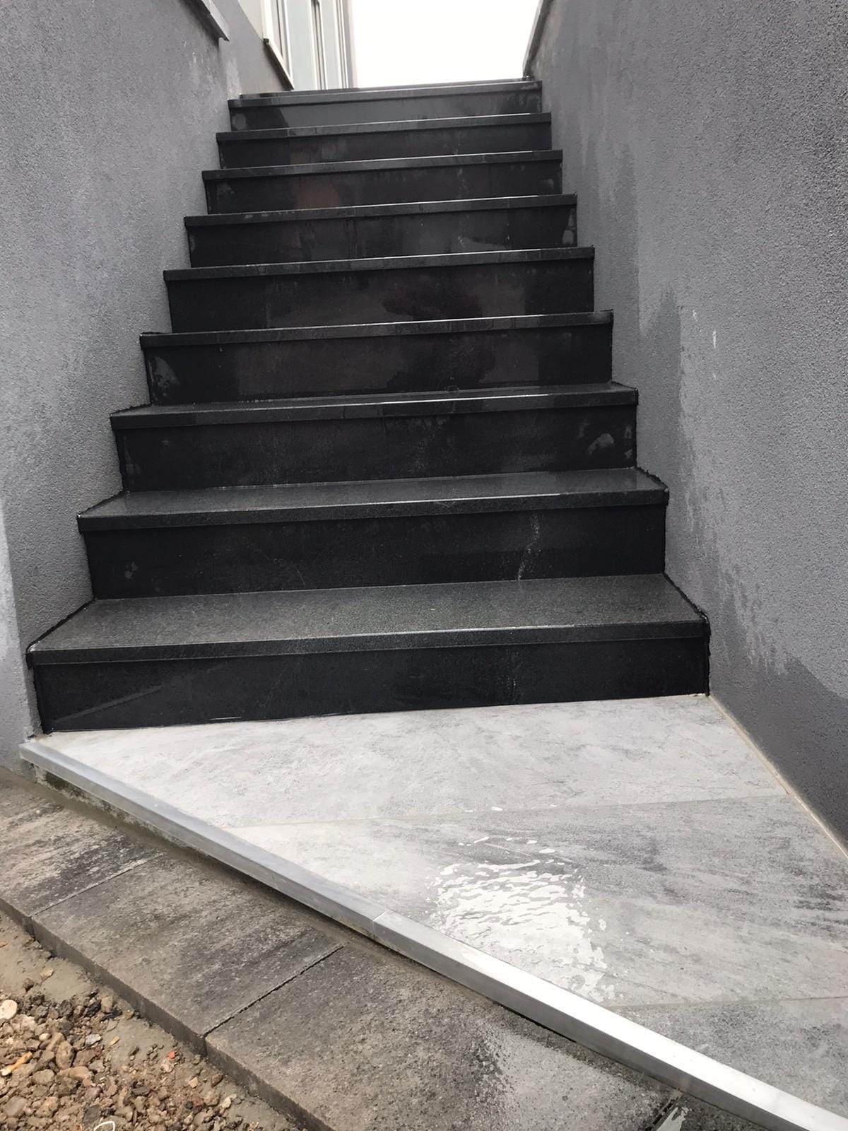 Escalier extérieur en pierre sombre reliant deux niveaux de terrasse