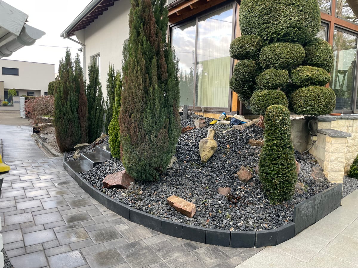 Jardin minéral associant cyprès taillés, enrochement et paillage ardoise
