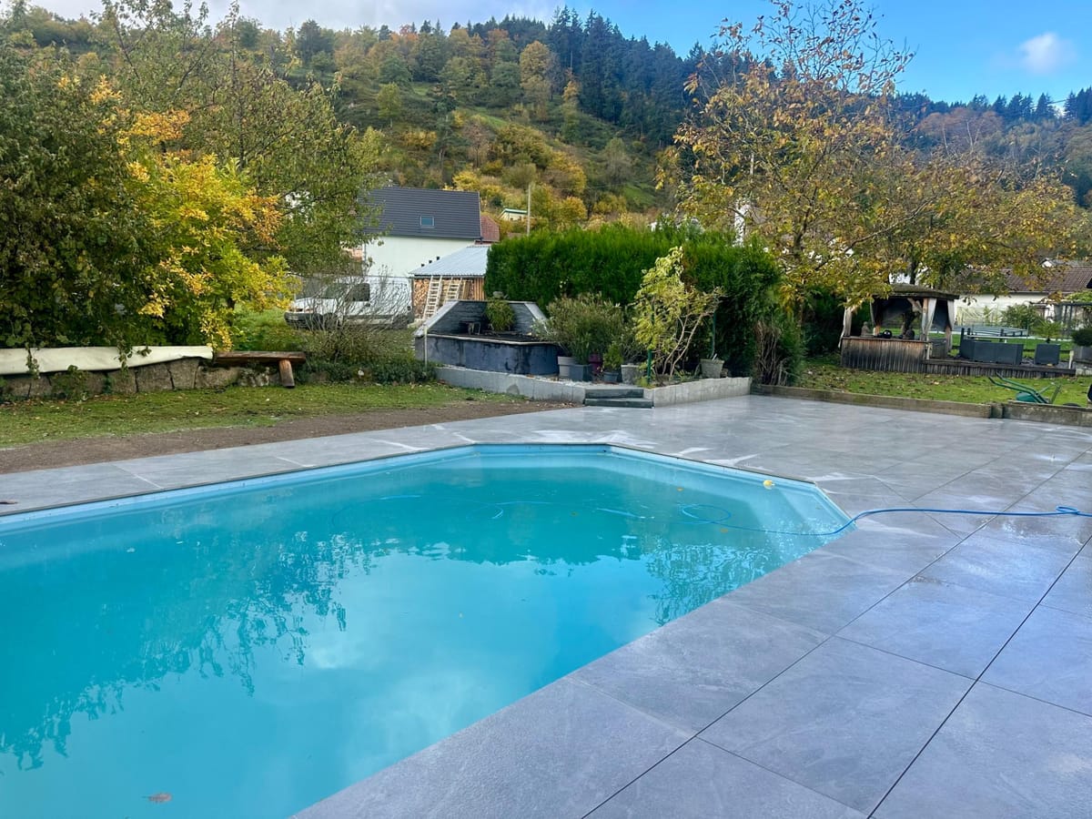 Piscine en béton avec plage en grandes dalles grises et pelouse attenante