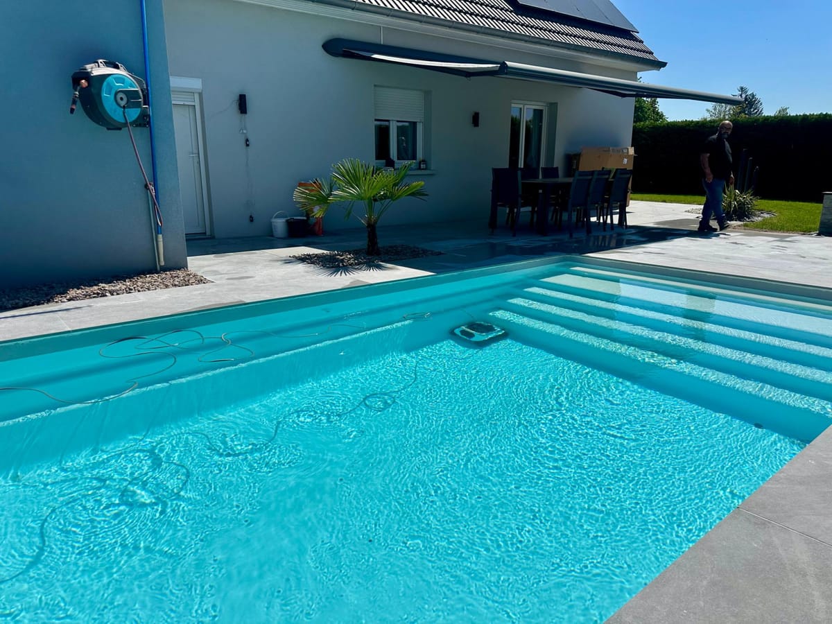 Piscine avec large escalier d'accès et margelles en pierre reconstituée