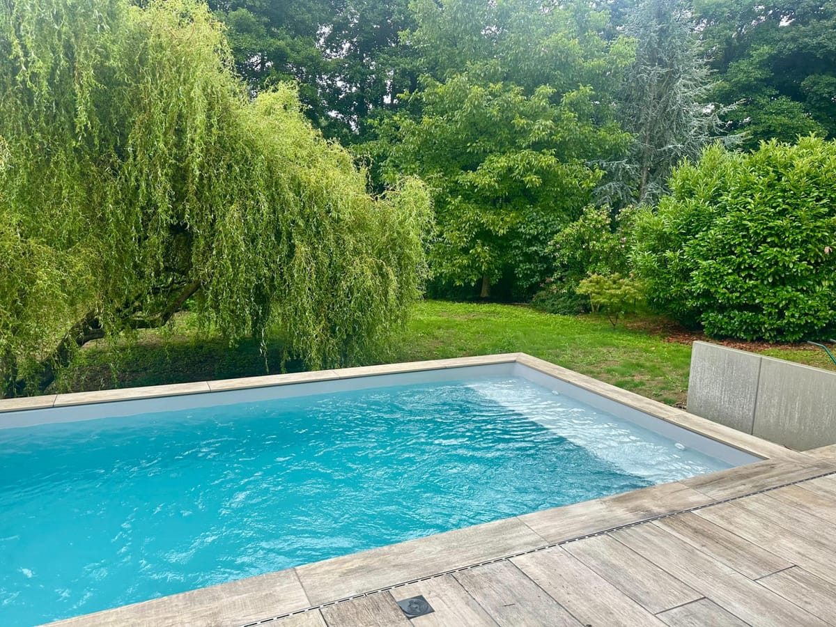 Piscine dans un jardin arboré avec saule pleureur en arrière-plan