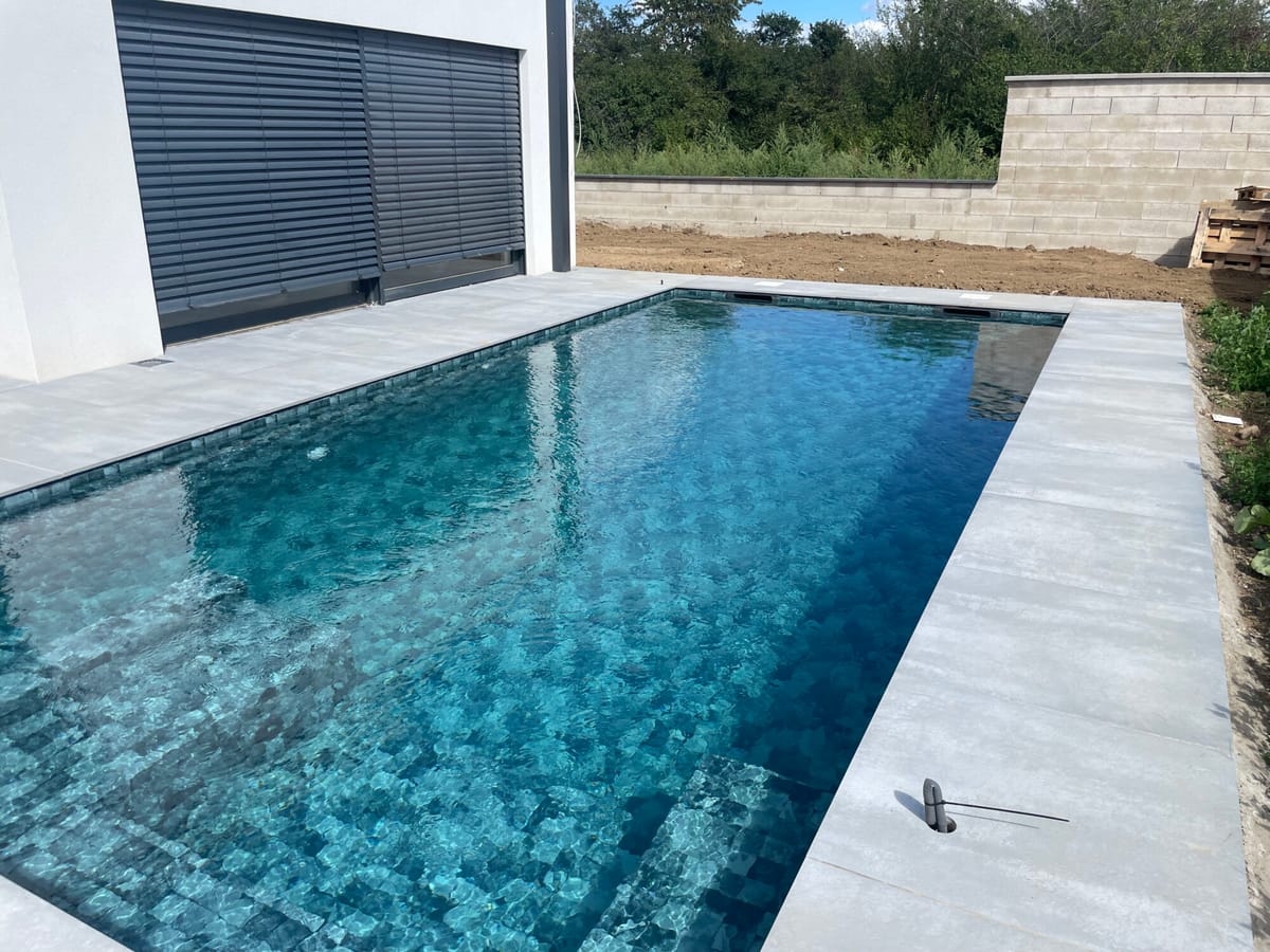 Piscine à revêtement mosaïque avec plage claire en cours de finition