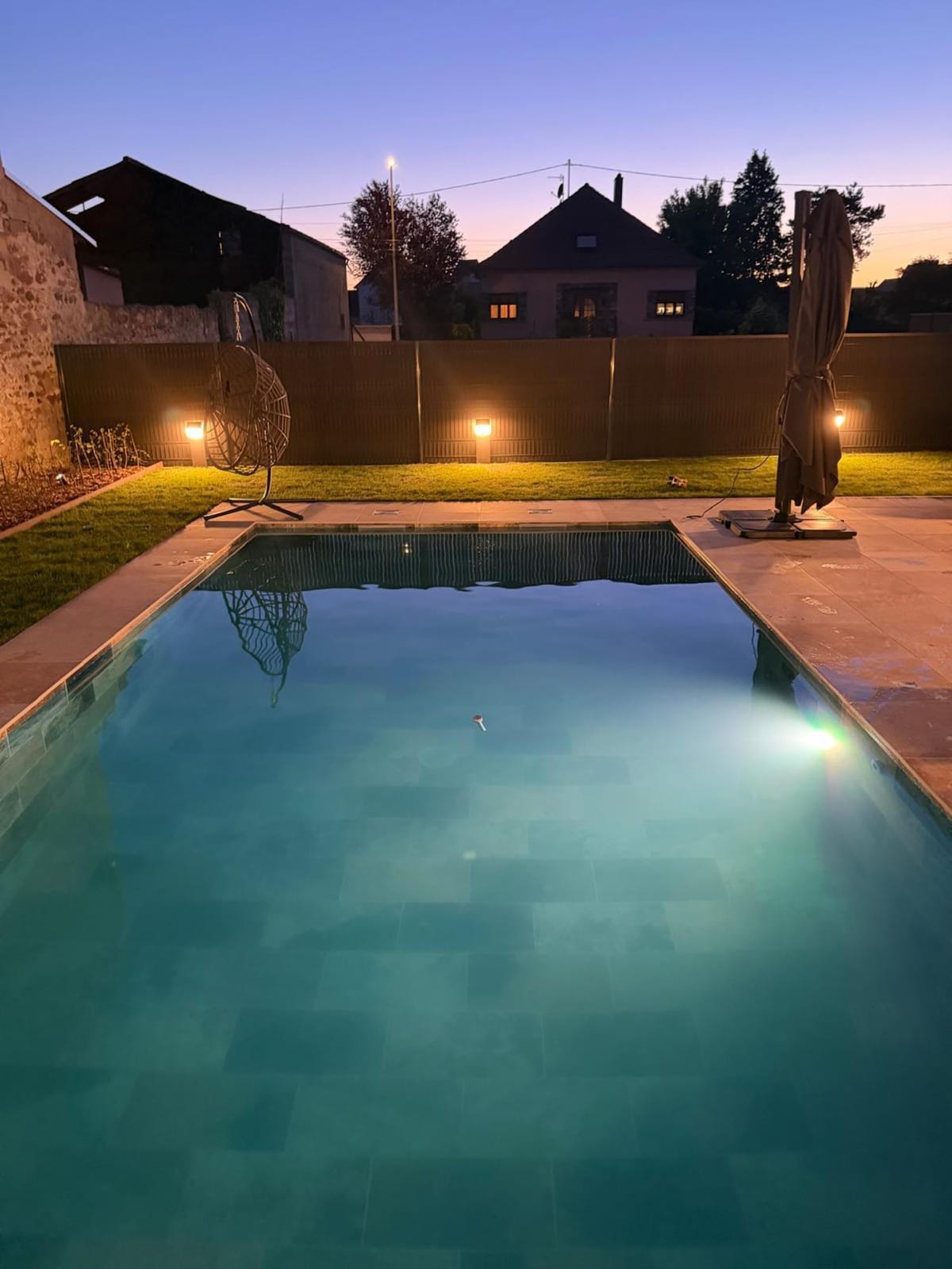 Piscine de nuit avec éclairage d'ambiance sur la façade et les abords