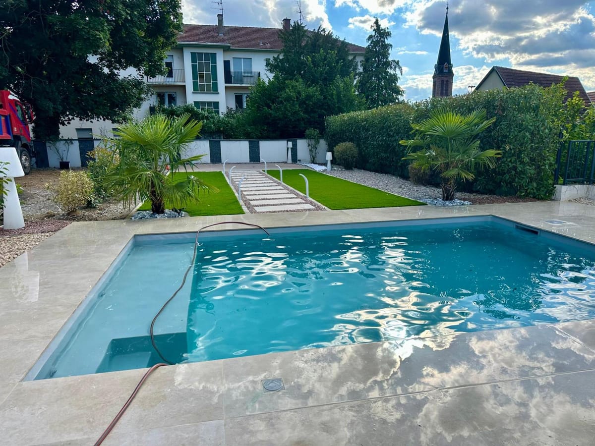 Piscine avec plage en dalles et jardin paysager à Pfastatt