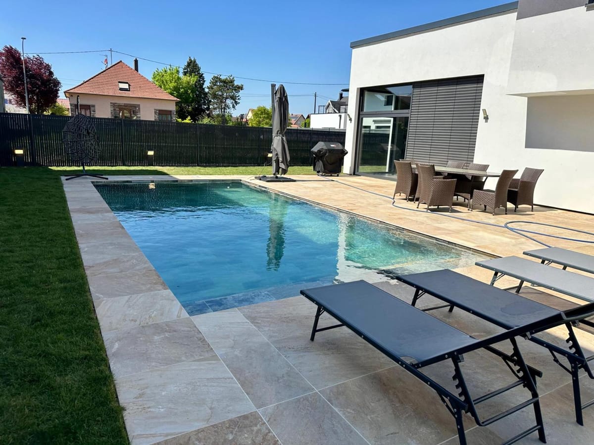 Piscine rectangulaire bordée d'une terrasse et d'un salon de jardin