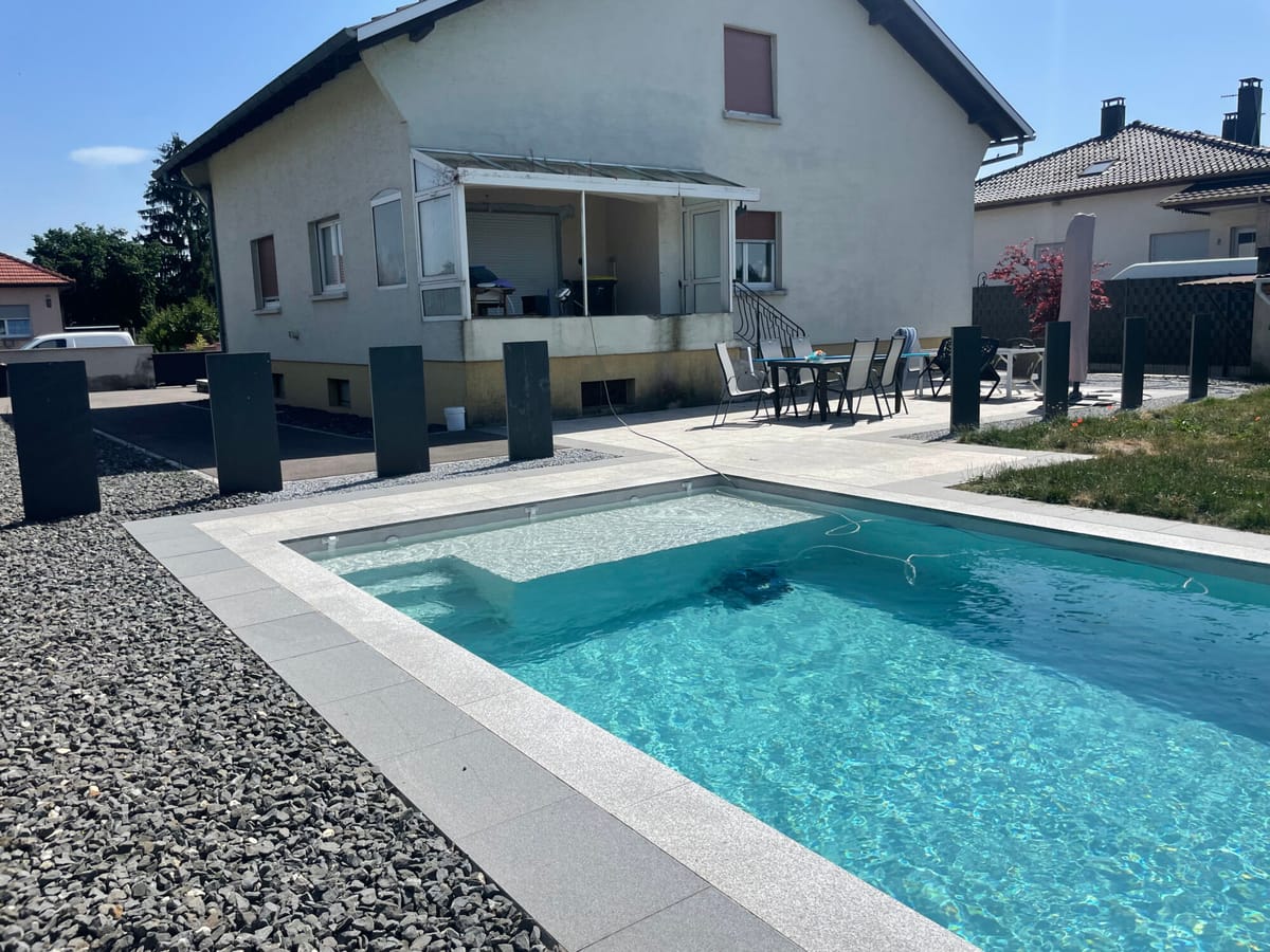 Piscine et terrasse aménagées devant une maison alsacienne